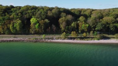 Sahil üzerinde insansız hava aracı ve plajlı şehir ormanının yanındaki tren yolu.