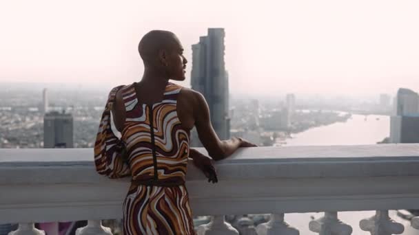 Μόδας μοντέλο ποζάροντας σε στροβιλιζόμενα ρούχα μοτίβο κοιτάζοντας πάνω από την πόλη — Αρχείο Βίντεο