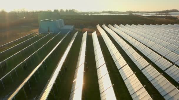 Dron powyżej promieni słonecznych paneli słonecznych w polu o zachodzie słońca — Wideo stockowe