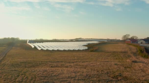 Drone volo verso il campo di pannelli solari in righe illuminate dal sole — Video Stock