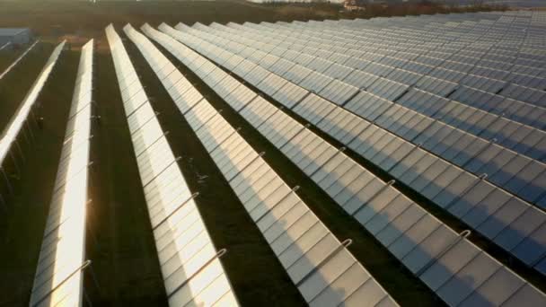 Dron nad sluncem osvětlené řádky solárních panelů v poli při západu slunce — Stock video