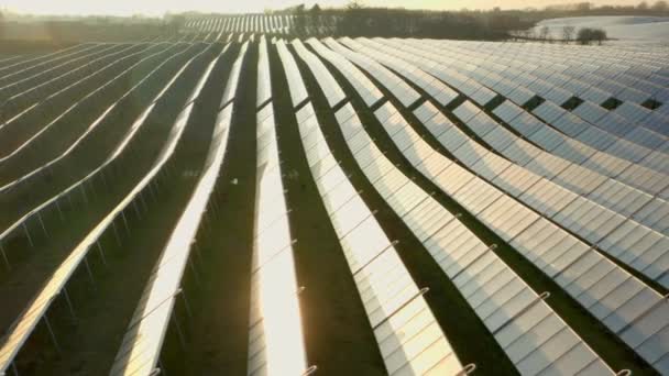 Drone sobre filas iluminadas por el sol de paneles solares en el campo al atardecer — Vídeos de Stock