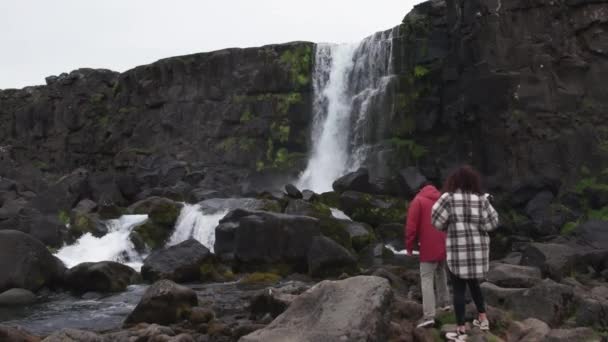 Pareja caminando hacia la cascada de Oxararfoss en Thingvellir — Vídeo de stock