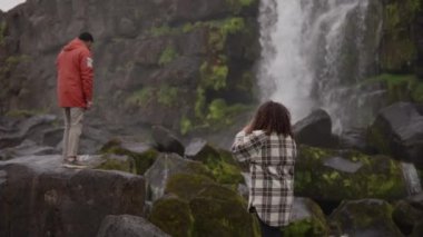 Oxararfoss Şelalesini İzleyen Adam için Eski Kamerayı Kullanan Kadın