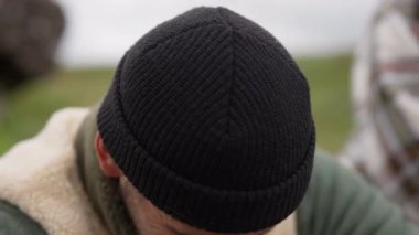 Yünlü şapkalı gülen adam gülüyor ve uzaklara bakıyor.