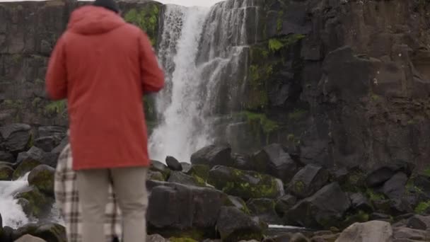 Pareja caminando hacia la cascada de Oxararfoss en Thingvellir — Vídeos de Stock
