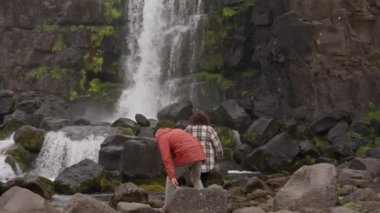 Kayaların üzerinden Oxarfoss 'a doğru adım atan çift.
