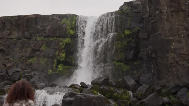 Kvinnan tittar på Oxarfoss vattenfall — Stockvideo