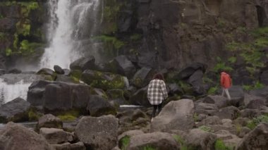 Kayaların üzerinden Oxarfoss 'a doğru adım atan çift.