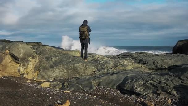 Muž s batohem fotografie vlnící se moře z kamení — Stock video