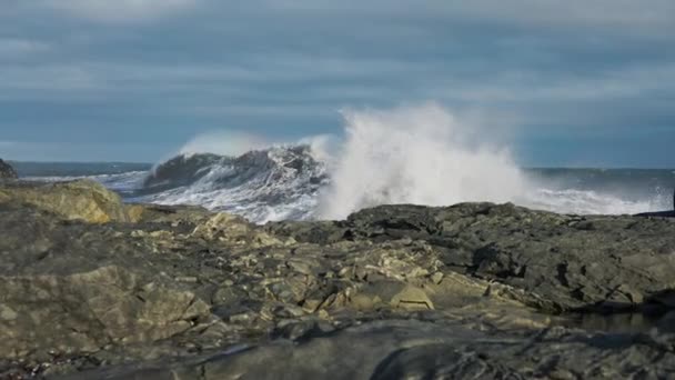 Człowiek z plecakiem chodzący po skałach jak fale uderzające do brzegu — Wideo stockowe