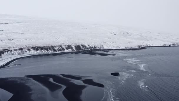 Drone Over Low Tide On Black Sand Beach And Snowy Landscape — Stock Video