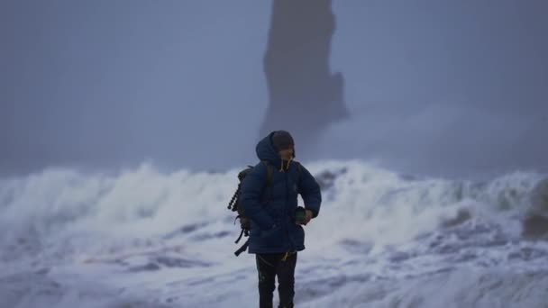 Fotógrafo en playa de arena negra con mar tormentoso — Vídeos de Stock