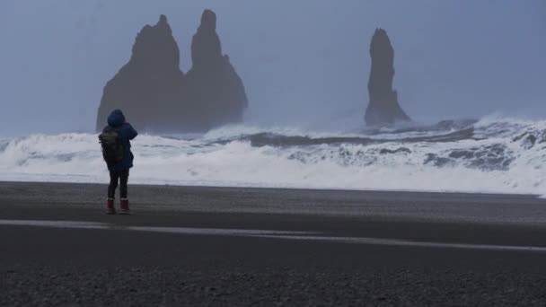 Фотограф На пляжі Чорного піску з штормовим морем — стокове відео