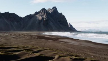 Drone, Vestrahorn manzaralı, dalgaların üstünde ve sahilde yükseliyor.
