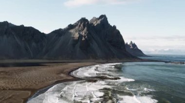 Drone, Vestrahorn manzaralı, dalgaların üstünde ve sahilde yükseliyor.