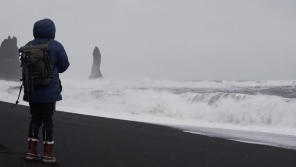 Photographer Standing On Black Sand Beach With White Sea — Vídeos de Stock