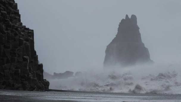 Olas de tormenta golpeando las pilas de mar y la playa de arena negra — Vídeo de stock