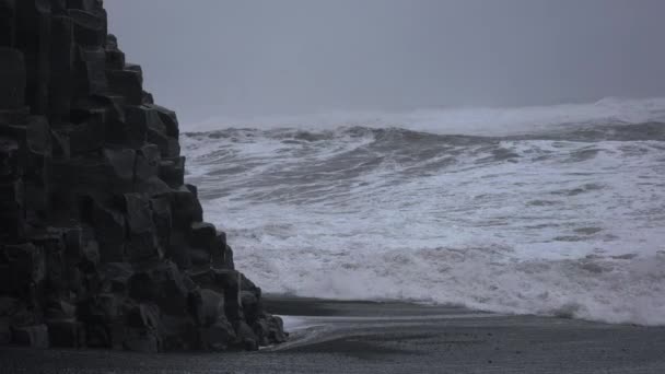 Sea Stack am schwarzen Sandstrand mit krachenden Wellen — Stockvideo