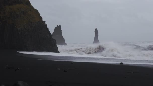 Witte branding crashen in rotsen op zwart zand strand — Stockvideo