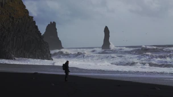 Фотограф На пляжі Чорного піску спостерігає за розбурханим морем — стокове відео