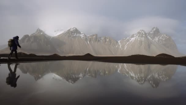 Hikers Walking Along Beach, Reflected In Seawater Pool With Mountains — ストック動画