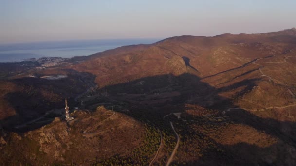 Drone over toren in rollend landschap bij zonsondergang — Stockvideo