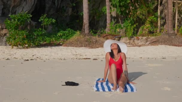 Kobieta w stroju kąpielowym i Sunhat opalająca się na plaży — Wideo stockowe