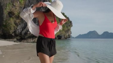 Güneş Şapkalı Kadın Entalula Sahili açıklarında denize bakıyor