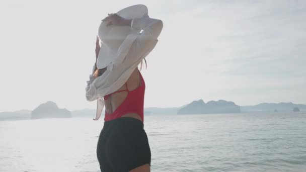 Mujer quitándose el sombrero de sol mientras camina en el mar frente a la playa de Entalula — Vídeo de stock