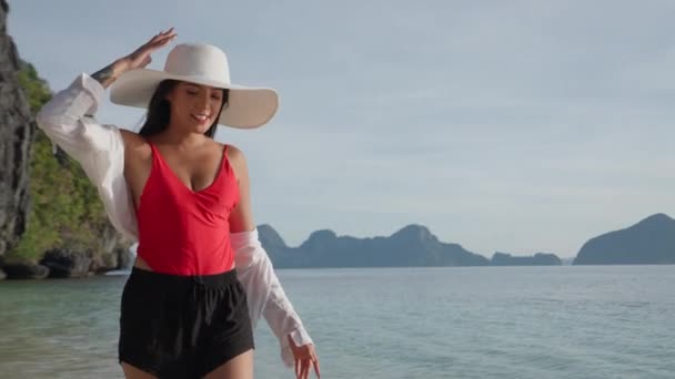 Mujer en sombrero de sol sonriendo y caminando en el mar frente a la playa de Entalula — Vídeos de Stock