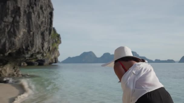Mujer en sombrero de sol caminando en el mar frente a la playa de Entalula — Vídeo de stock