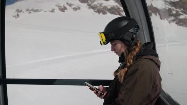 ケーブルカーで携帯電話で赤い縞とスカイウェアのテキストを持つ女性 — ストック動画
