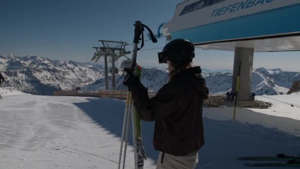 Mujer poniendo en esquís por teleférico y girando a sonreír — Vídeo de stock