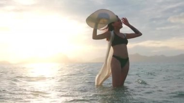 Bikini 'li Kadın, Güneş Şapkası Tutan, Gün batımında Denizde Duran