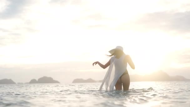 Γυναίκα σε στρινγκ περπατώντας στη θάλασσα καθώς δύει ο ήλιος — Αρχείο Βίντεο