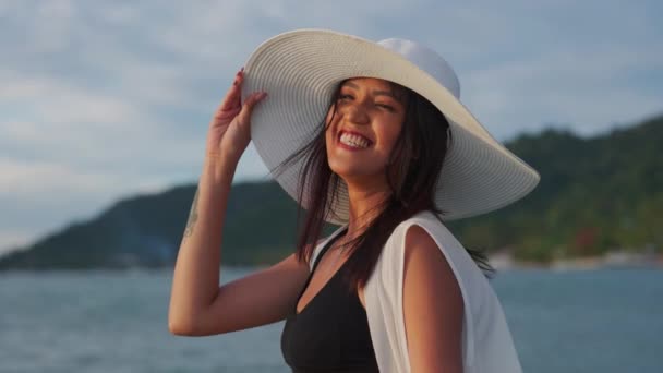 Mulher de biquíni e chapéu de sol sorrindo no mar ao pôr do sol — Vídeo de Stock