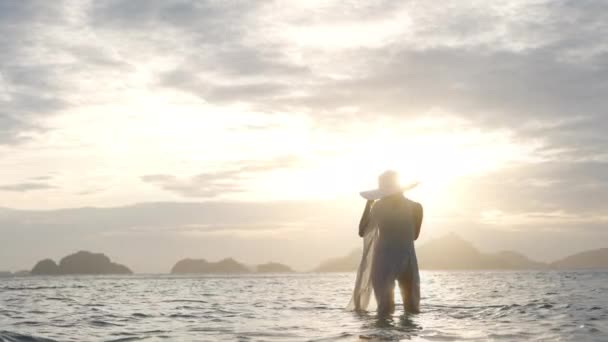 Femme en bikini et chapeau de soleil debout en mer comme coucher de soleil — Video