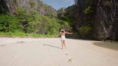 Kadın koşuyor ve kumsaldaki kameraya gülümsüyor.