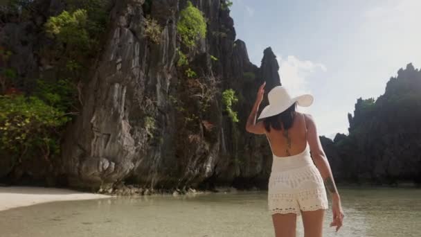 Vrouw wandelen langs zonovergoten verborgen strand — Stockvideo