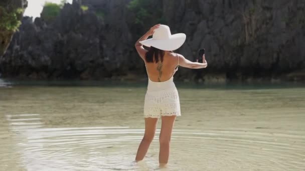 Женщина позирует для селфи в море на скрытом пляже — стоковое видео