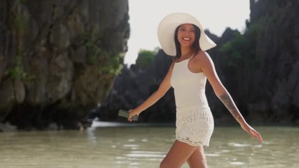 Glimlachende jonge vrouw wandelen langs in de zon hoed — Stockvideo