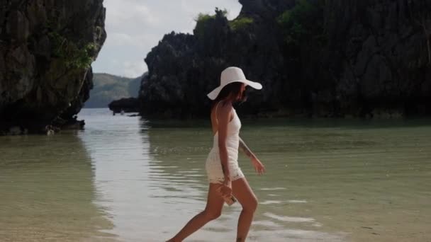 Jeune femme au chapeau de soleil coups de pied Tidewater sur la plage cachée — Video