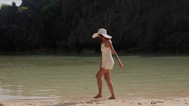 Молодая женщина в солнечной шляпе ходит в приливной воде — стоковое видео