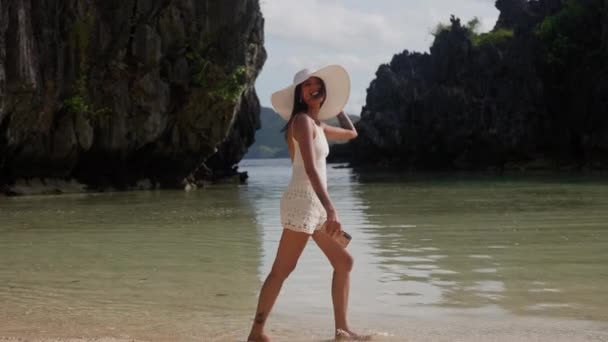 Mladá žena v klobouku kráčející v přílivové vodě — Stock video