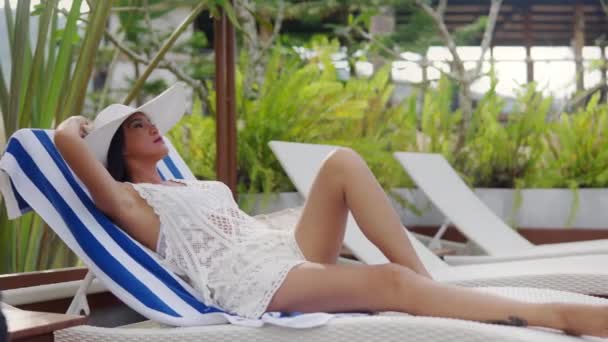 Woman In Sun Hat Relaxing On Sun Lounger At Resort Poolside — Vídeo de Stock