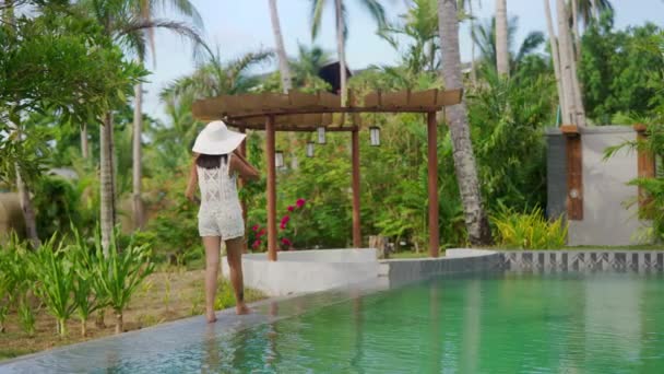 Woman In Sun Hat Walking Along Poolside In Resort — Wideo stockowe