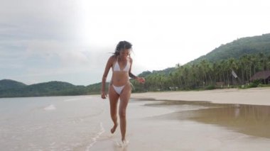 Young Woman In Bikini Running Along Beach