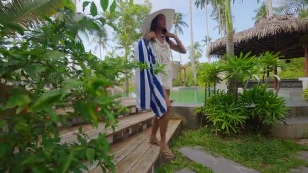 Woman In Sun Hat Walking With Beach Towel On Resort Path — Wideo stockowe