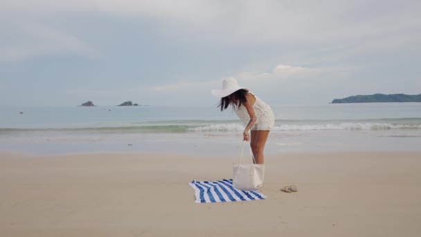 Vrouw in de zon hoed regelen tas en strand handdoek — Stockvideo